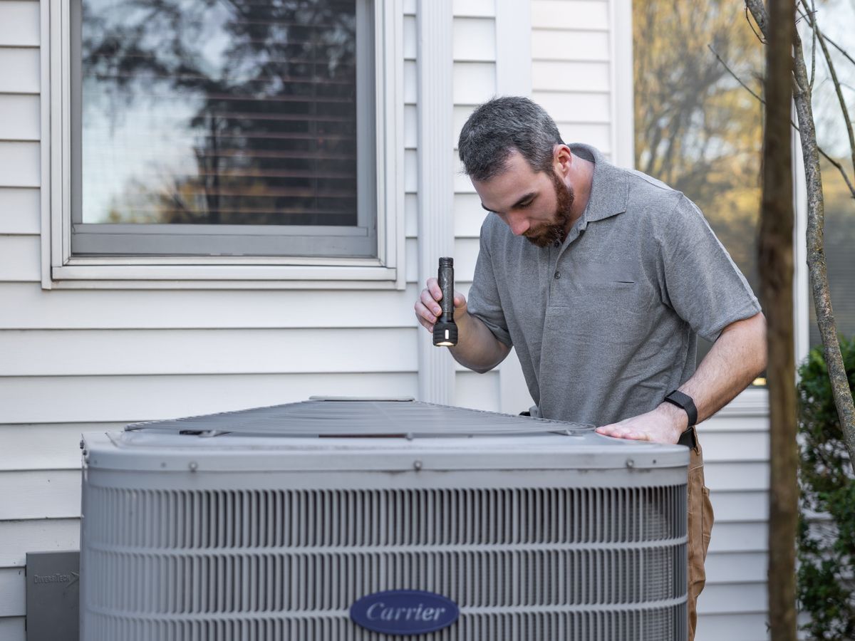 HVAC technician diagnosing a residential air conditioning condenser unit