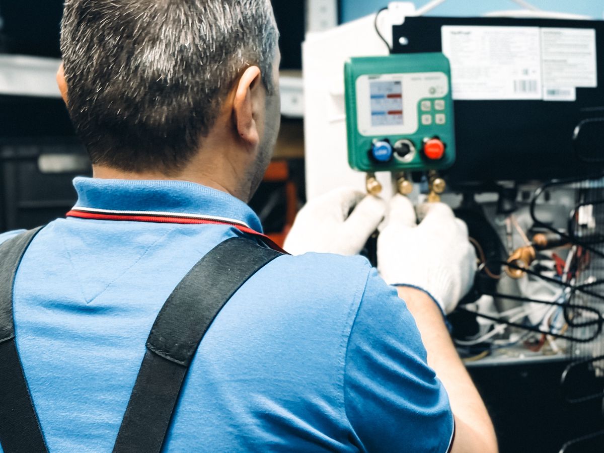 Technician using manifold gauges to check refrigerant charge on an AC system