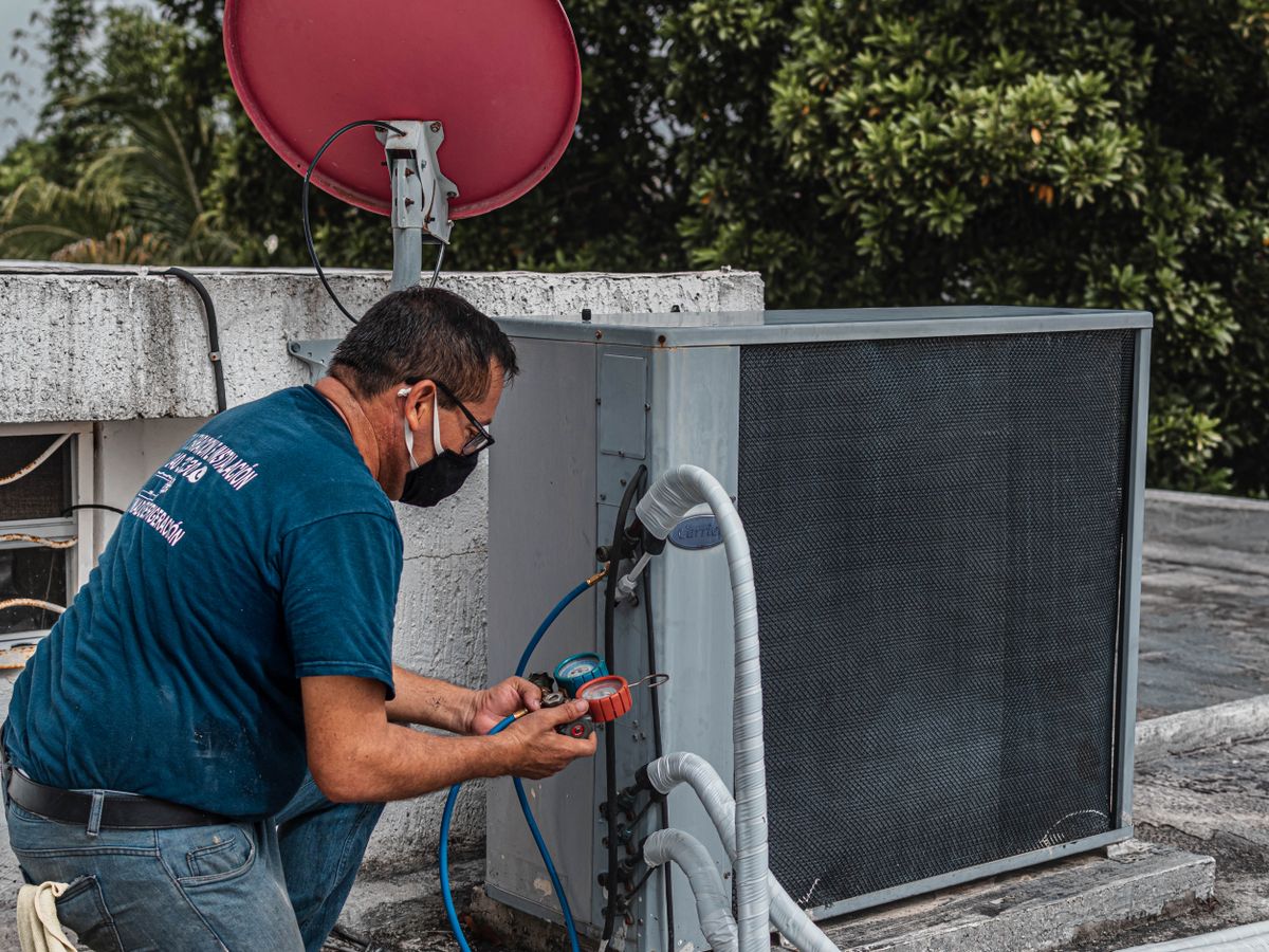 HVAC technician testing air conditioning electrical components with a meter