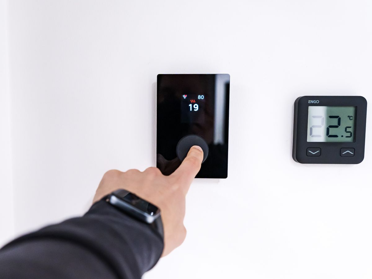 Homeowner adjusting a modern smart thermostat on the wall